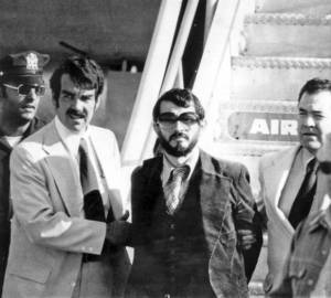 1976 photo shows Zvonko Busic, with beard, being led from plane in custody of police at New York's Kennedy Airport after he and four companions returned from Paris to face charges of air piracy and murder.